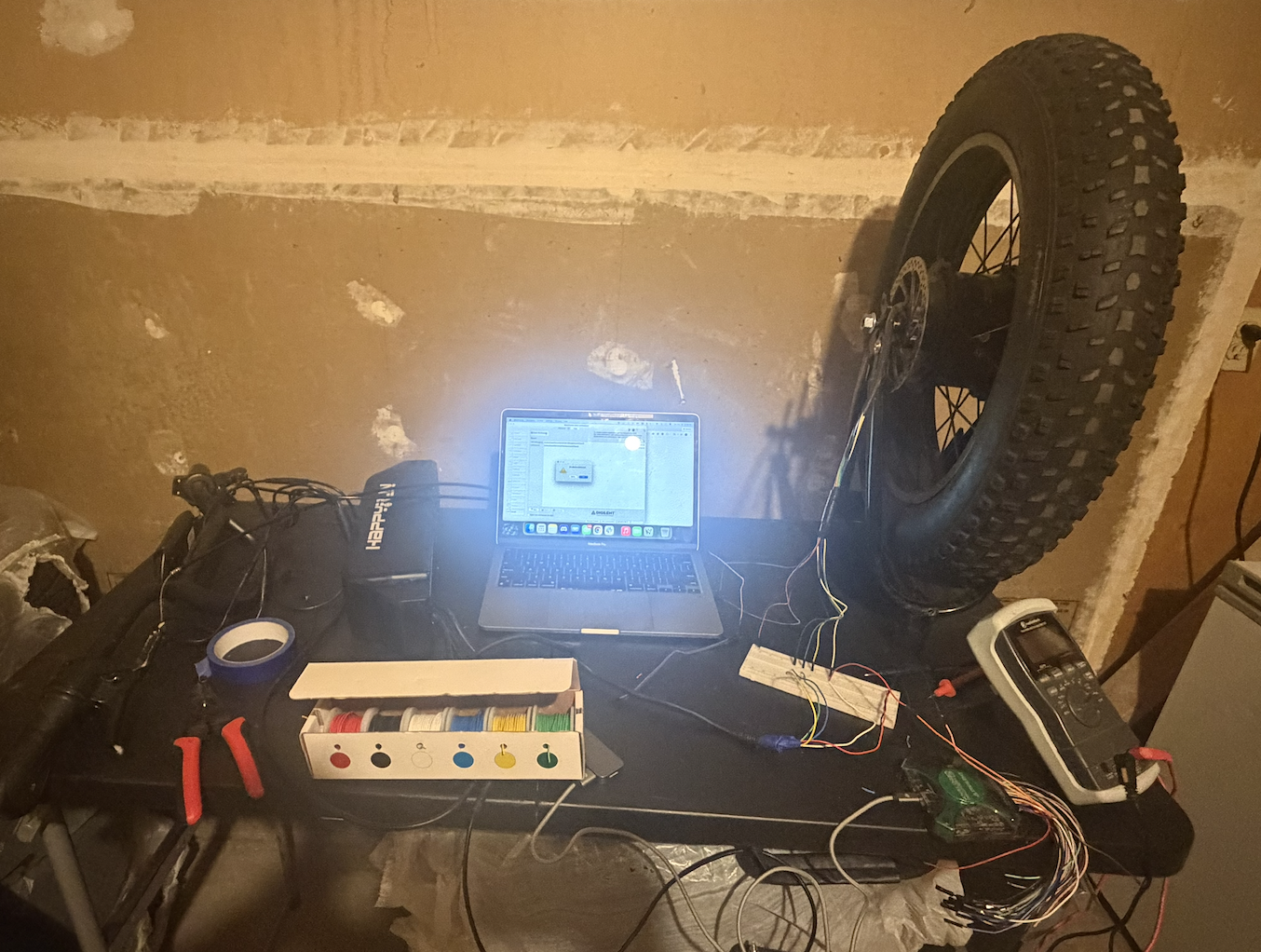 The e-bike electronics and test gear spread across a workbench.