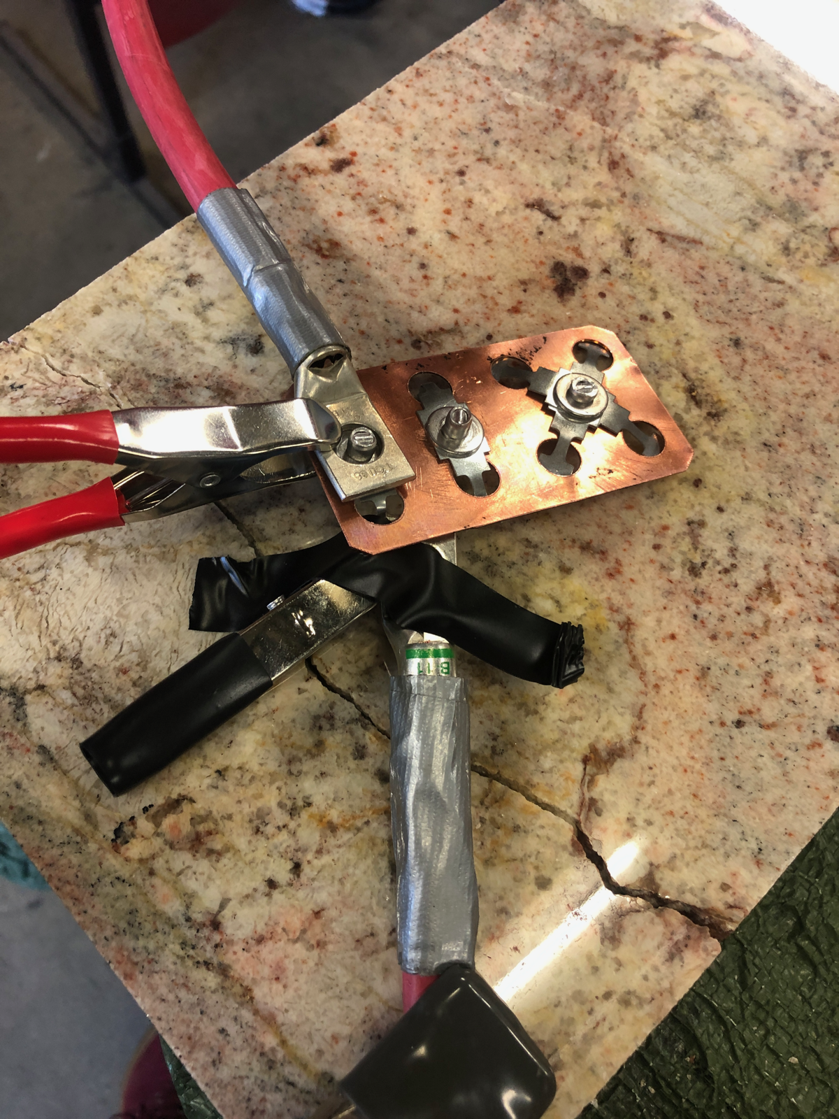 A close-up of the fuse test fixture connected with high-current clamps.