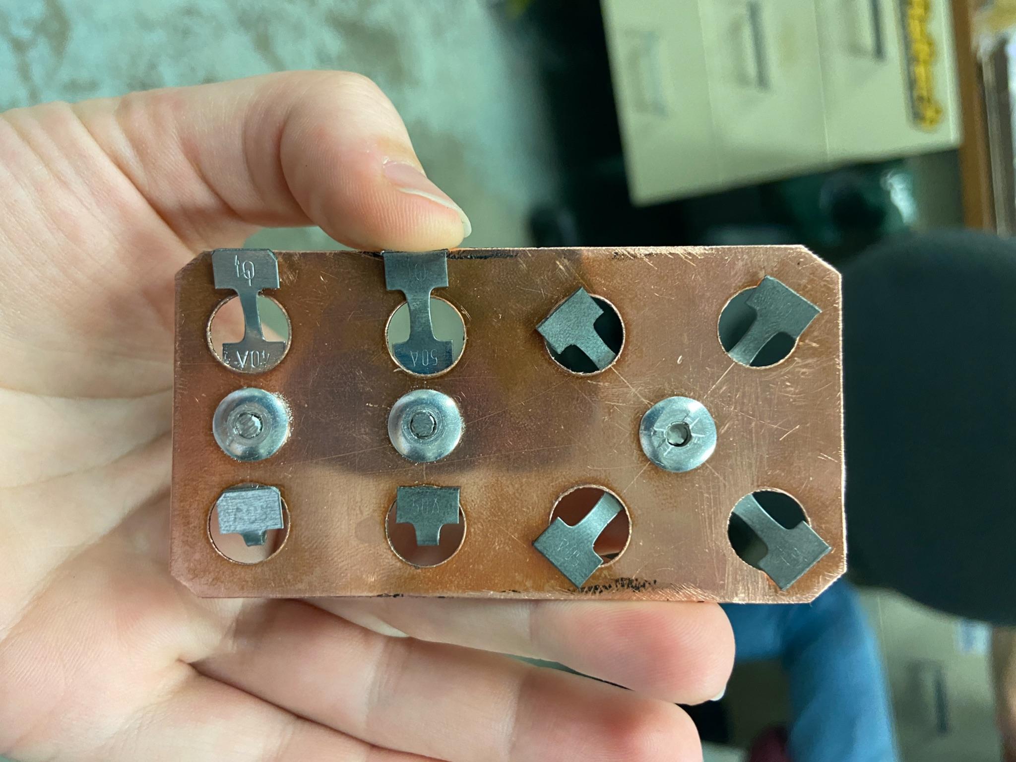 A prototype copper bus bar with riveted commercial strip fuses.