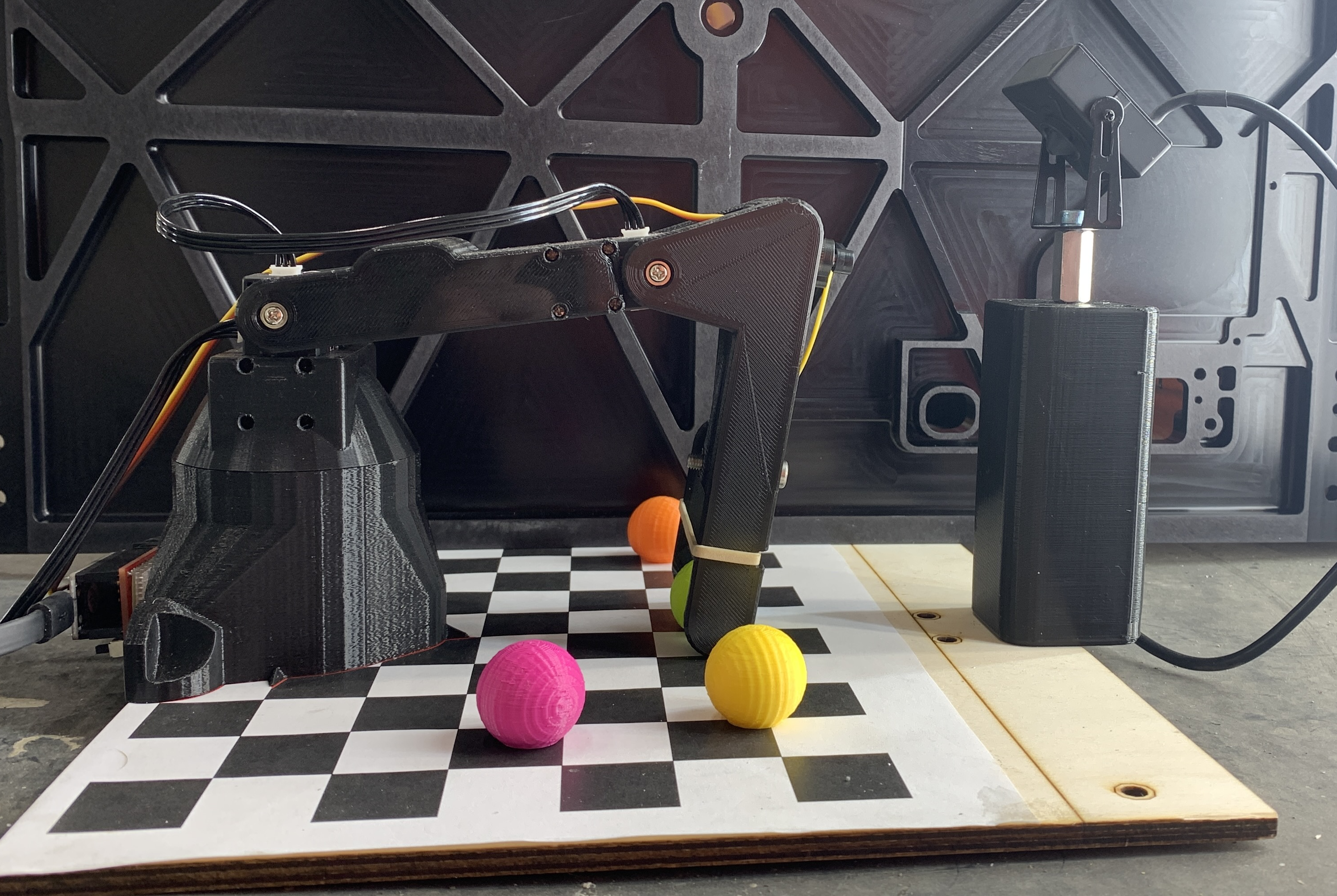 A robot arm and camera positioned over a checkerboard sorting workspace.